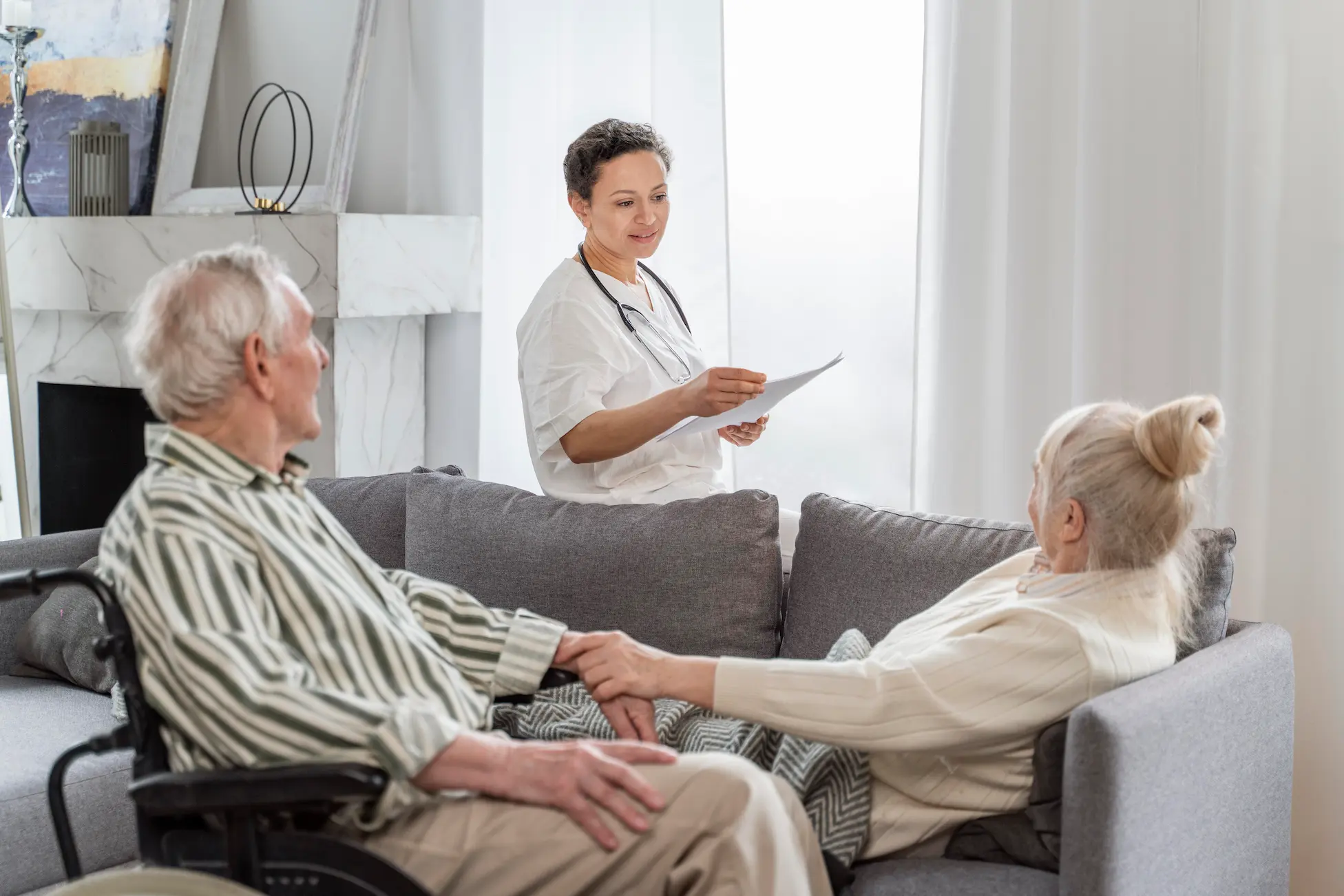 A couple sitting on a couch with a nurse.